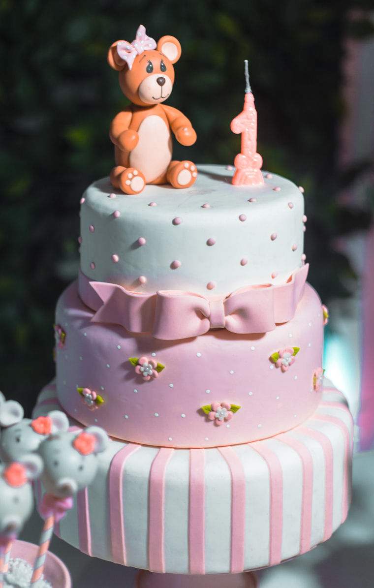 Three tier birthday cake
with pink, white and blue icing, the numeral 1 and a
teddy bear on the top
